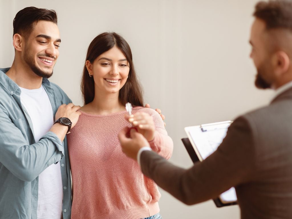 Dos personas entusiasmadas recibiendo las llaves de su nuevo departamento. Representa el contenido del texto: cómo comprar un departamento en Chile. 